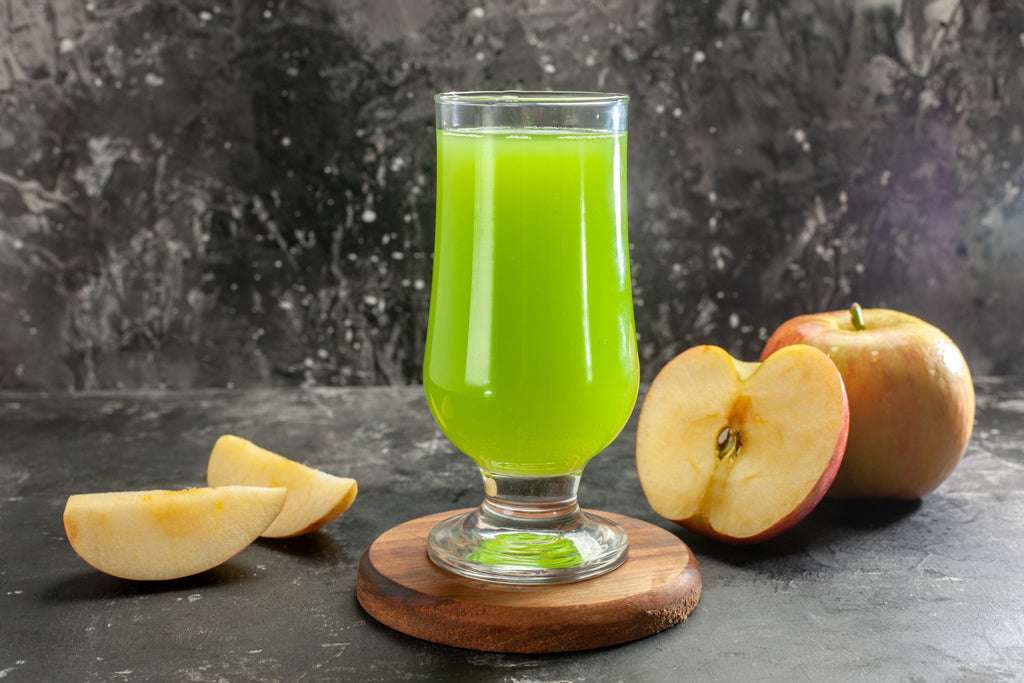 Glass of fresh organic apple juice with red and green apples in